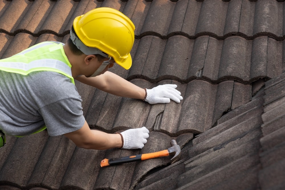 man repairing tile on roof